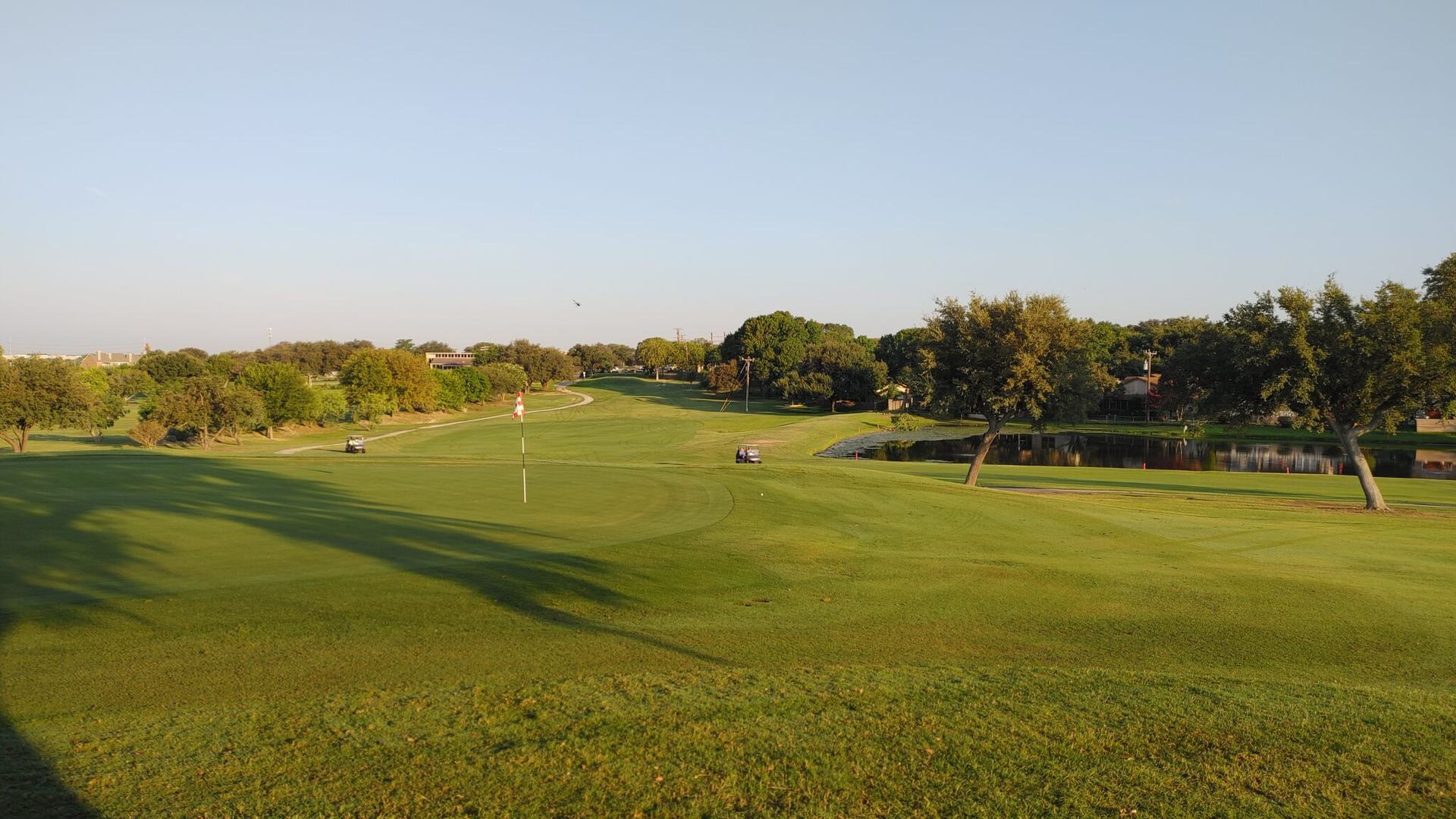 Fairway and golf carts among mature trees at Northern Hills Golf Course in San Antonio.