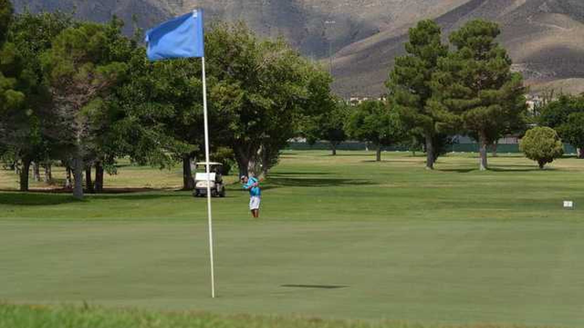 Golfer approaching a blue-flagged green on the Sunrise Course at Underwood Golf Complex.