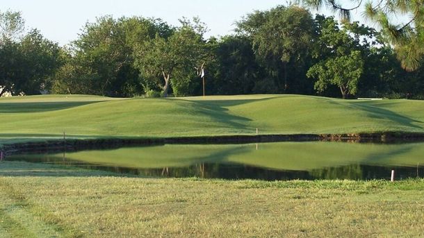 Green beside a pond and mature trees at Jersey Meadow Golf Course in Jersey Village.